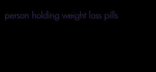 person holding weight loss pills
